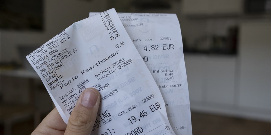 Hand houdt 2 kassabonnen van de supermarkt vast
