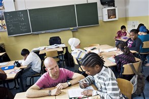 Leraar geeft huiswerkbegleiding aan een basisschoolleerling uit groep 8